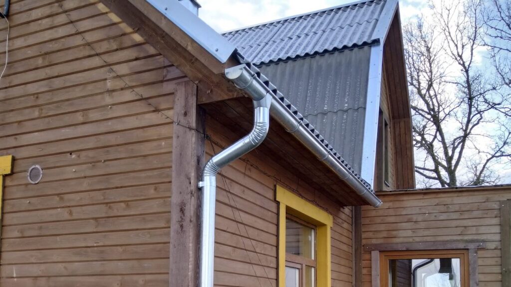 Leedu eterniit Klasika tsementhall viimistlus katusel, tsinkplekist vihmaveesüsteem ja lisaplekid puitfassaadiga eramajal